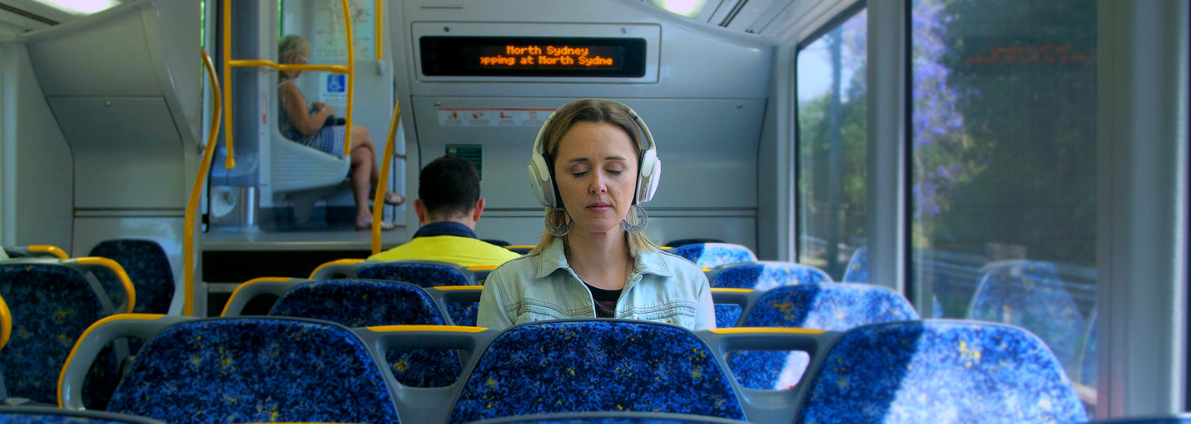 Lady wearing headphones in a train - My Year of Living Mindfully - THIS Buddhist Film Festival