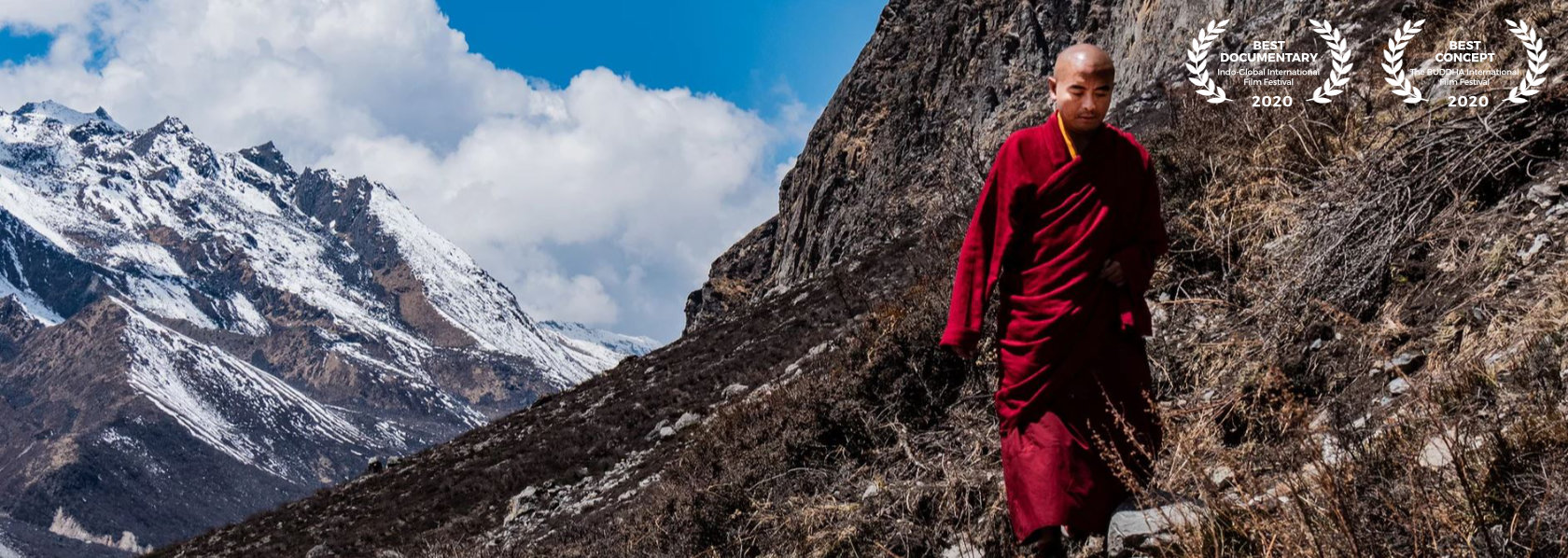 Mingyur Rinpoche looking down walking on a mountain with winter mountain blue sky background - Wandering But Not Lost - THIS Buddhist Film Festival